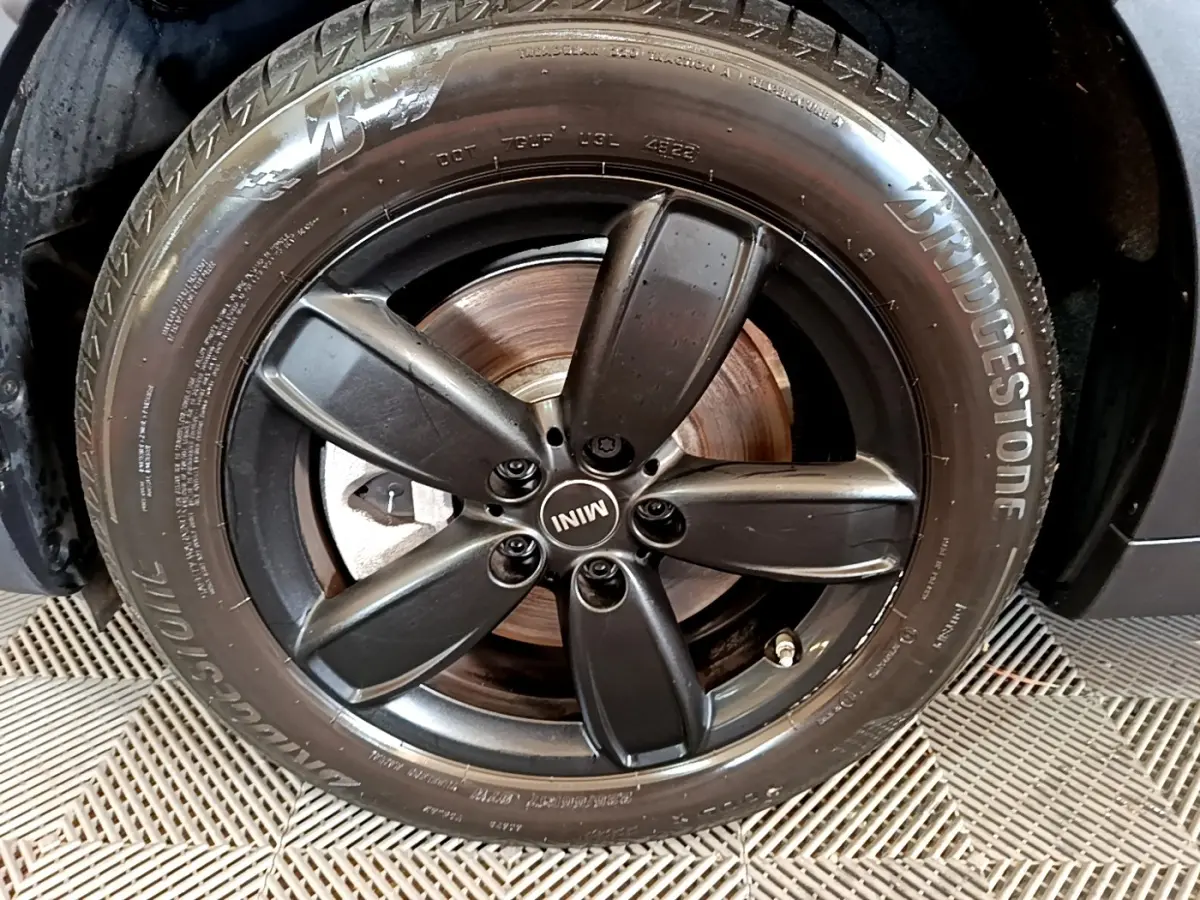 Gros plan sur la jante noire à cinq branches du MINI Countryman vert 2023 avec pneu Bridgestone visible.