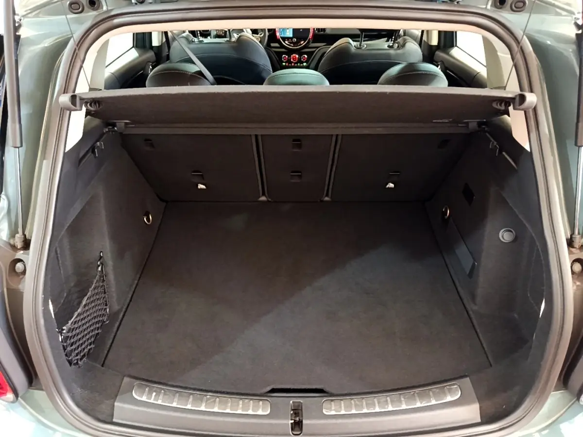 Coffre ouvert vu de l'arrière d'une MINI Countryman Cooper SE vert avec banquette arrière rabattable et cache-bagages.