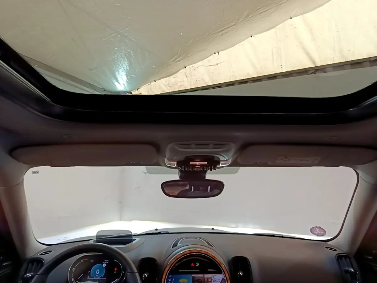Vue intérieure avant du MINI Countryman Cooper SE avec toit ouvrant panoramique et tableau de bord moderne.