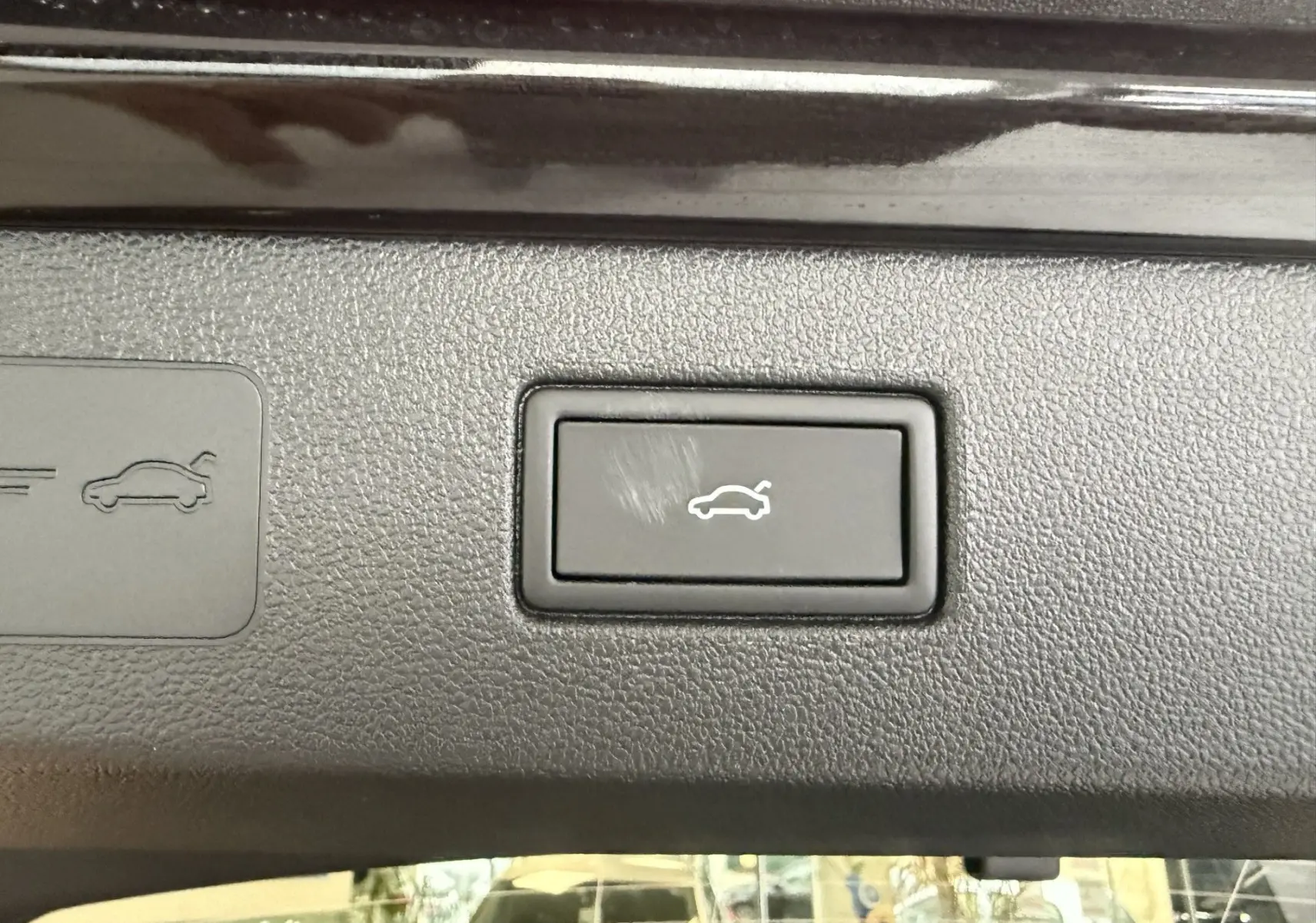 Bouton intérieur noir pour ouverture électrique du coffre sur Volkswagen T-Roc noir intense, vue rapprochée du tableau de bord.