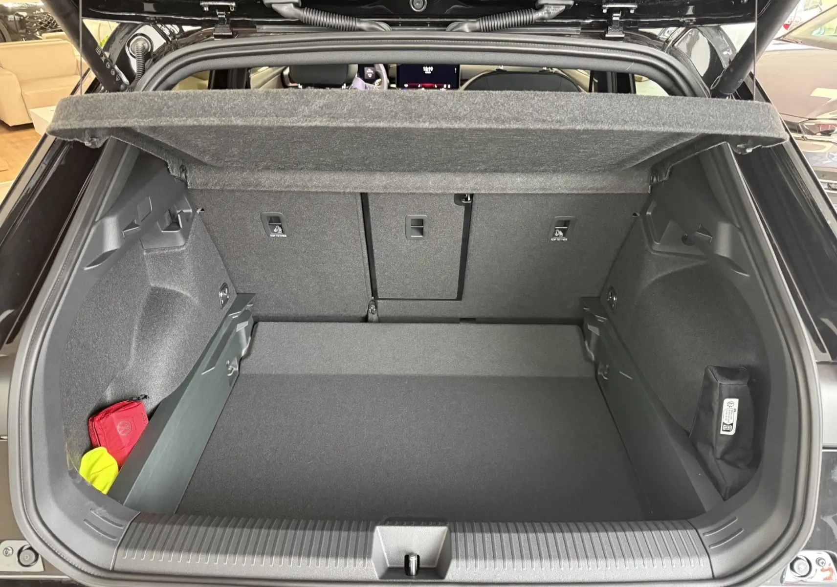 Coffre ouvert du Volkswagen T-Roc noir intense, vue arrière montrant un espace de chargement propre et bien organisé.