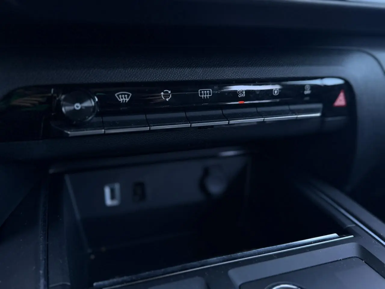 Détail du tableau de bord noir du Citroën C5 Aircross Hybrid 2025 montrant la rangée de commandes climatisation et prises USB.