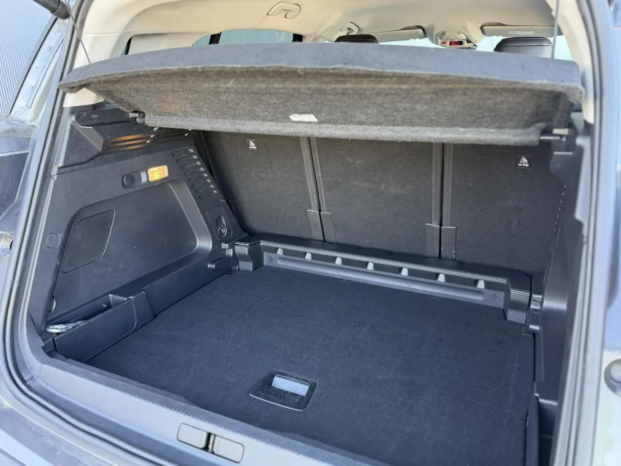 Coffre ouvert vu de l'arrière du Citroën C5 Aircross Hybrid gris Platinium, montrant la plage arrière et l'espace de chargement.
