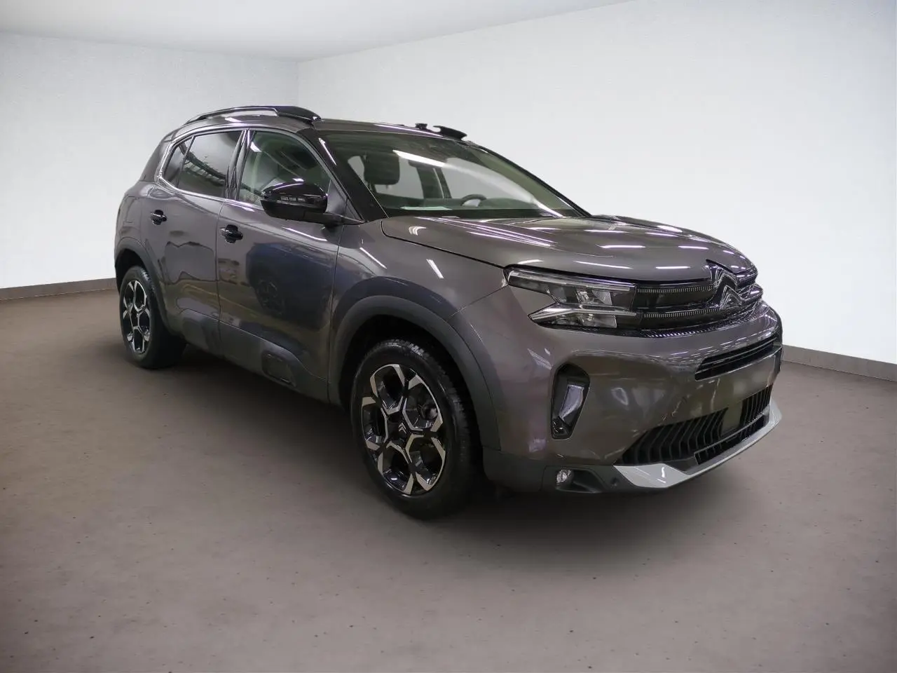 Citroën C5 Aircross Hybrid gris platinium vue 3/4 avant droit avec jantes alliage bi-ton et barres de toit noires.