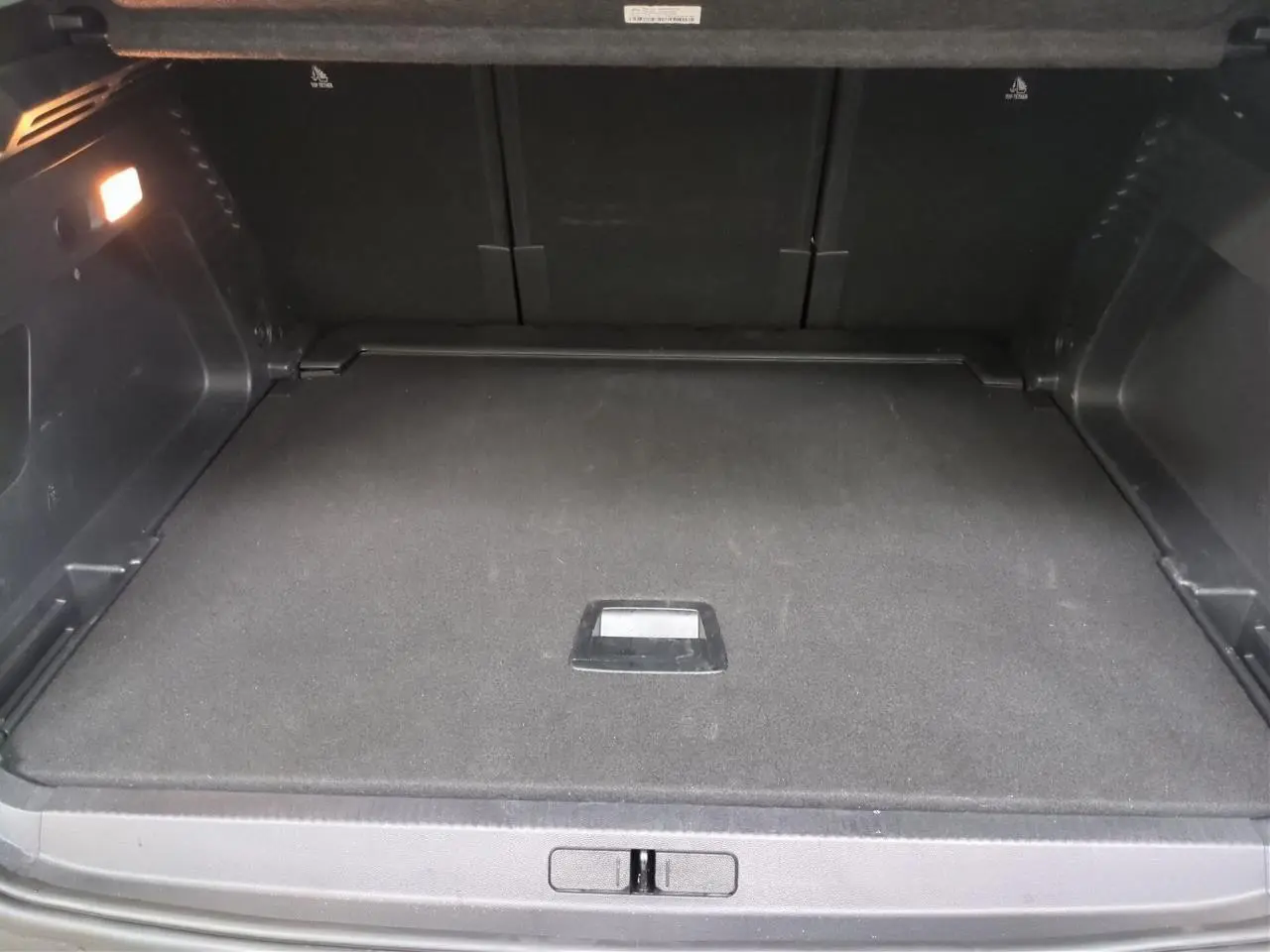 Coffre ouvert vu de l'arrière d'un Citroën C5 Aircross Hybrid gris Platinium avec hayon électrique et éclairage intérieur.