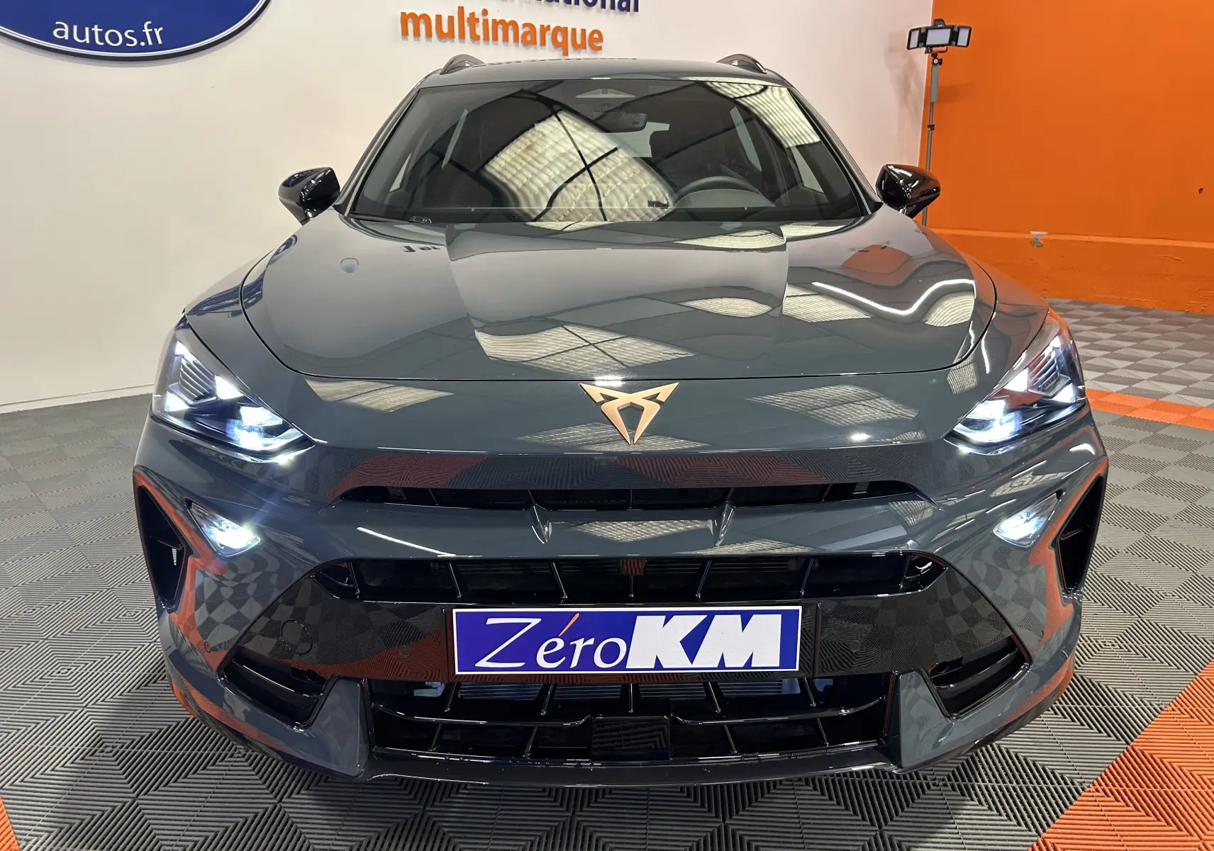 Vue frontale d'une CUPRA Formentor bleu fjord métal avec phares LED allumés dans un showroom.