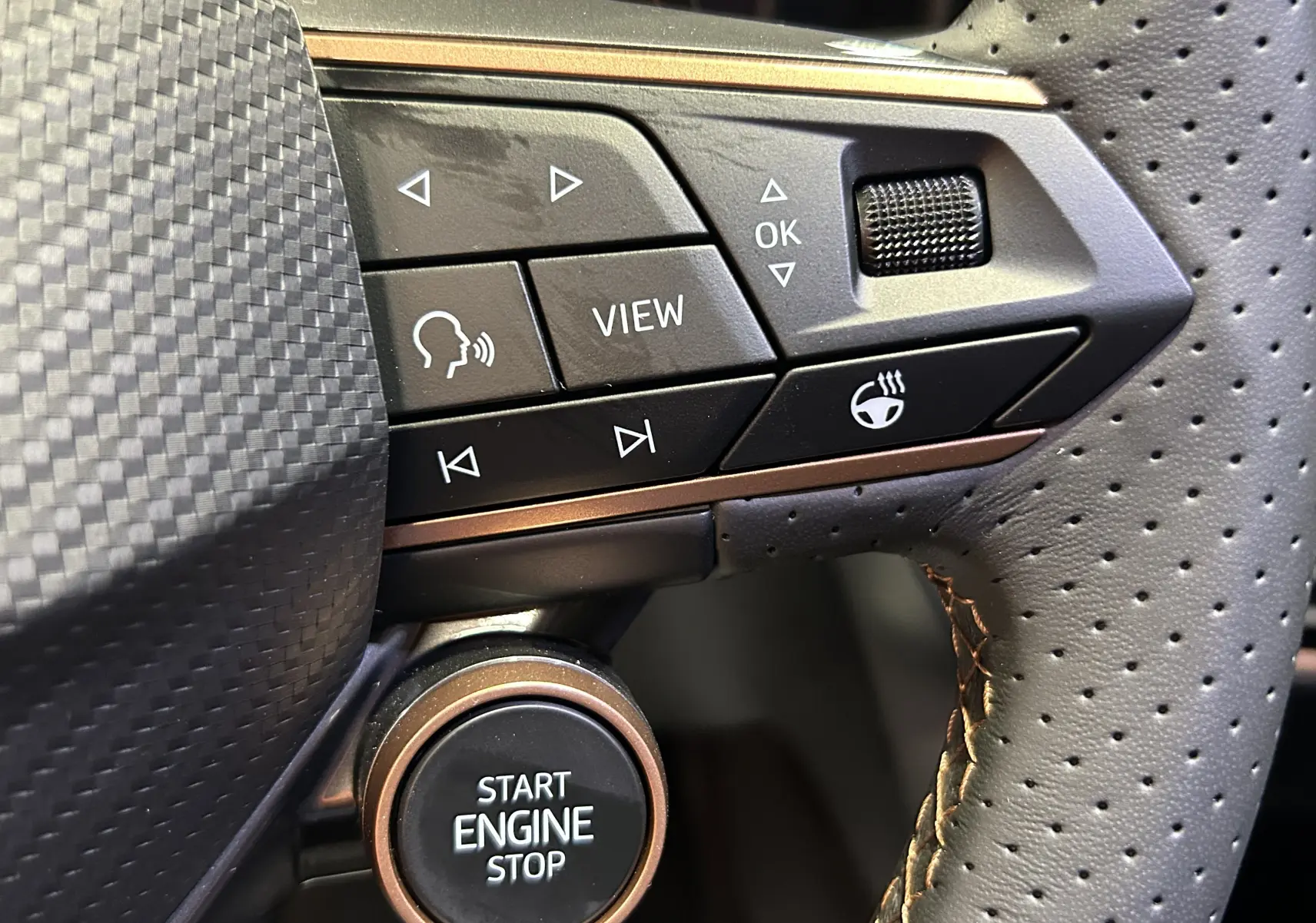 Gros plan sur les commandes du volant en cuir perforé noir de la Cupra Formentor, avec bouton start engine stop et touches multifonctions.