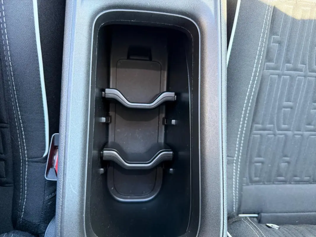 Gros plan sur le rangement central noir entre les sièges avant d'une Fiat 600 T-Gen 3 blanche, intérieur tissu gris.