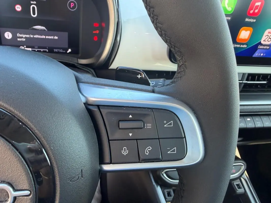Gros plan sur la partie droite du volant noir de la Fiat 600 T-Gen 3 blanc, avec commandes audio et téléphone visibles.