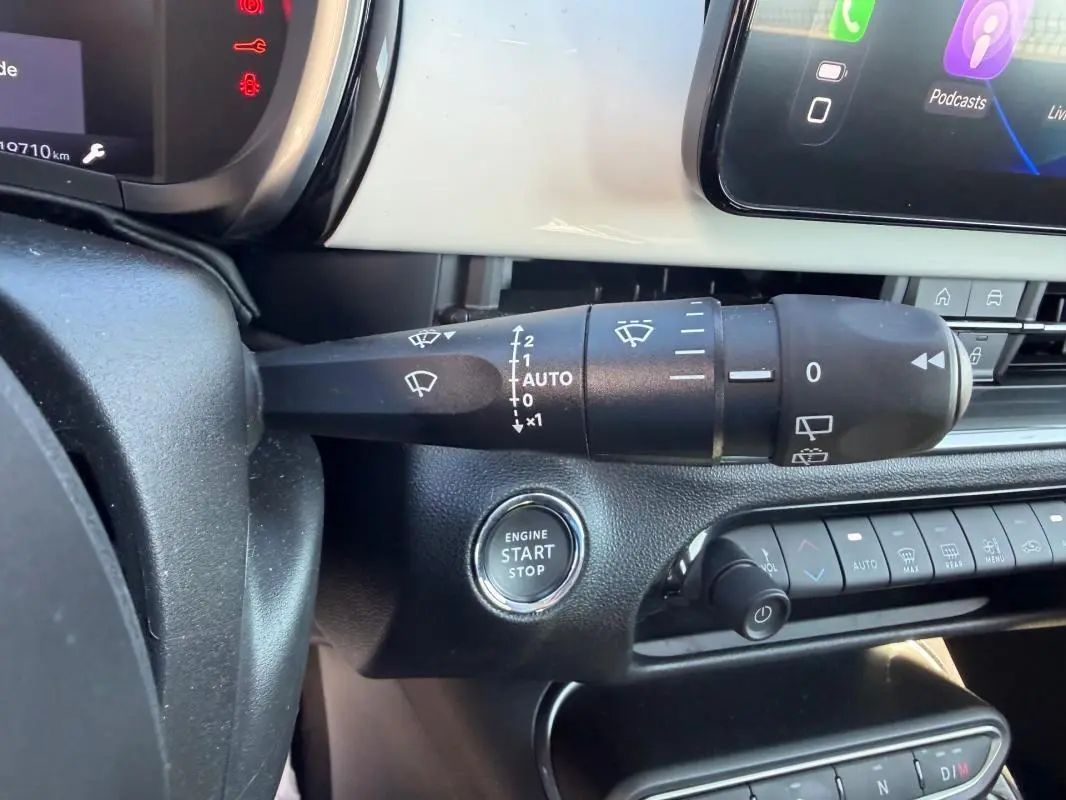Gros plan sur la commande d’essuie-glace et le bouton start/stop du tableau de bord intérieur d’une Fiat 600 blanche.