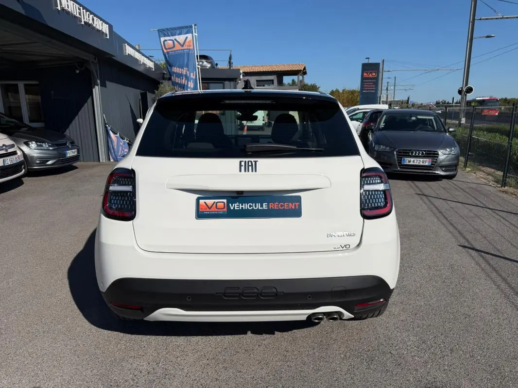 Vue arrière d'une FIAT 600 blanche 2025 avec feux arrière noirs et double sortie d'échappement visible.