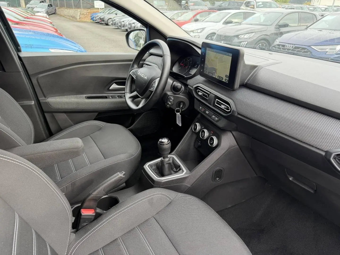 Intérieur de la Dacia Jogger 2025 vu côté conducteur, tableau de bord avec écran tactile et volant multifonction.