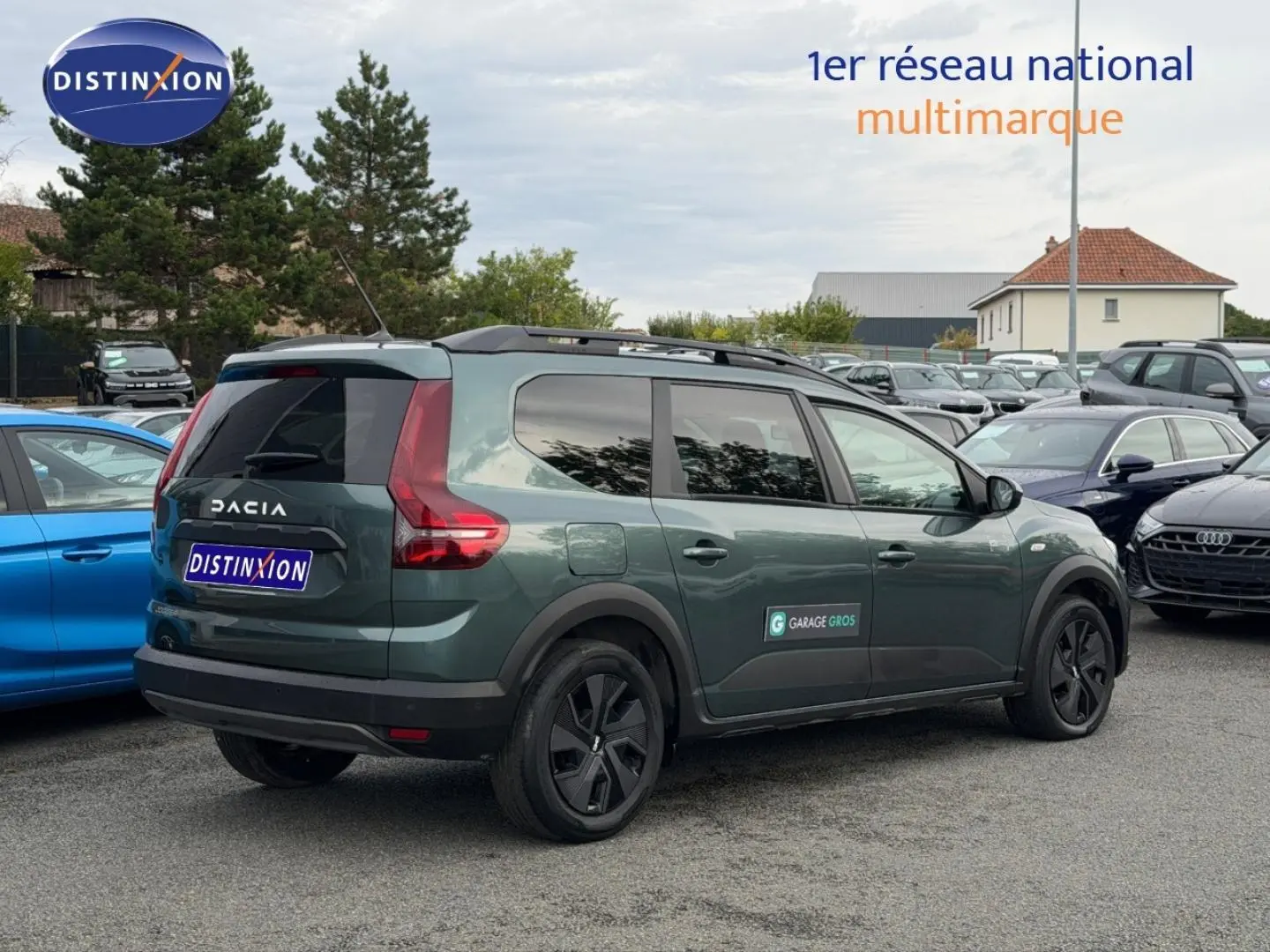 Vue 3/4 arrière droite d'un Dacia Jogger 2025 vert cèdre métallisé avec barres de toit et vitres teintées.