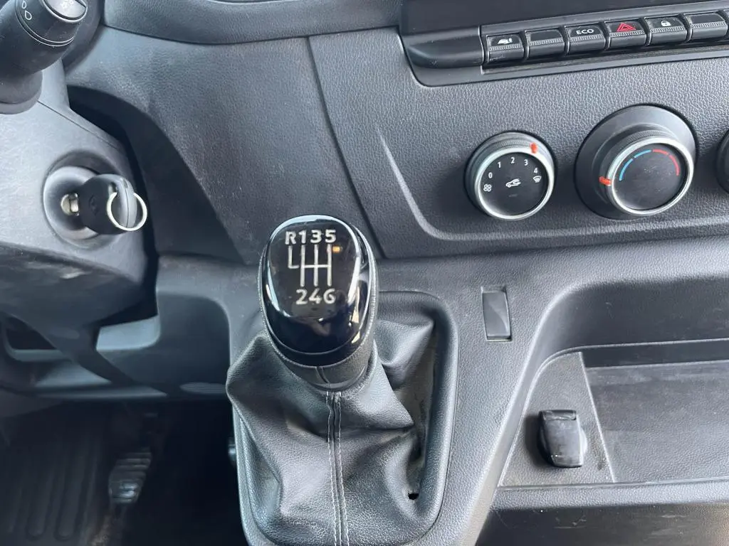 Gros plan sur levier de vitesses manuel noir et commandes de climatisation du tableau de bord d'un Renault Master blanc 2020.