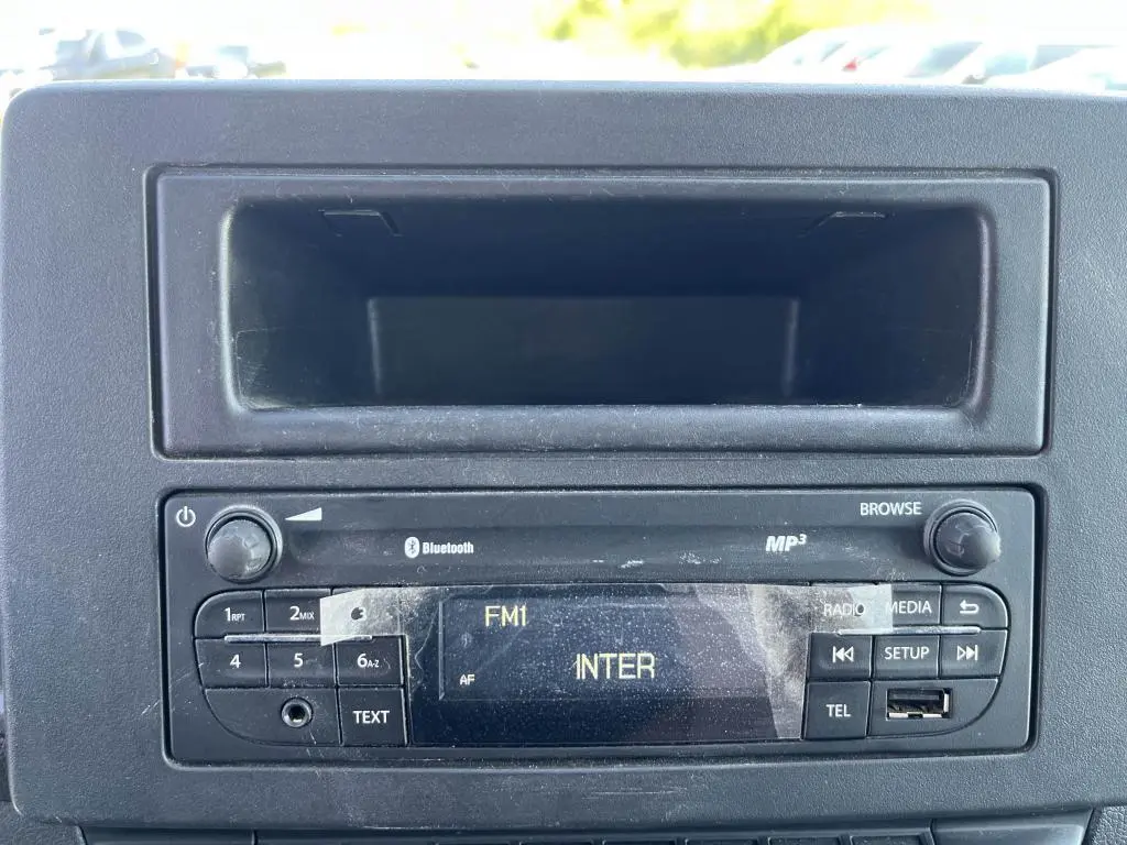 Radio d'origine avec écran FM et commandes intégrées sur le tableau de bord noir du Renault Master blanc.