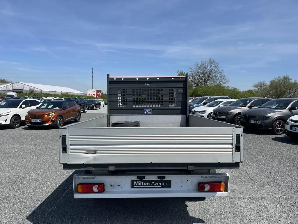 Vue arrière d'un Renault Master blanc avec plateau ridelles aluminium et cabine double sur un parking.