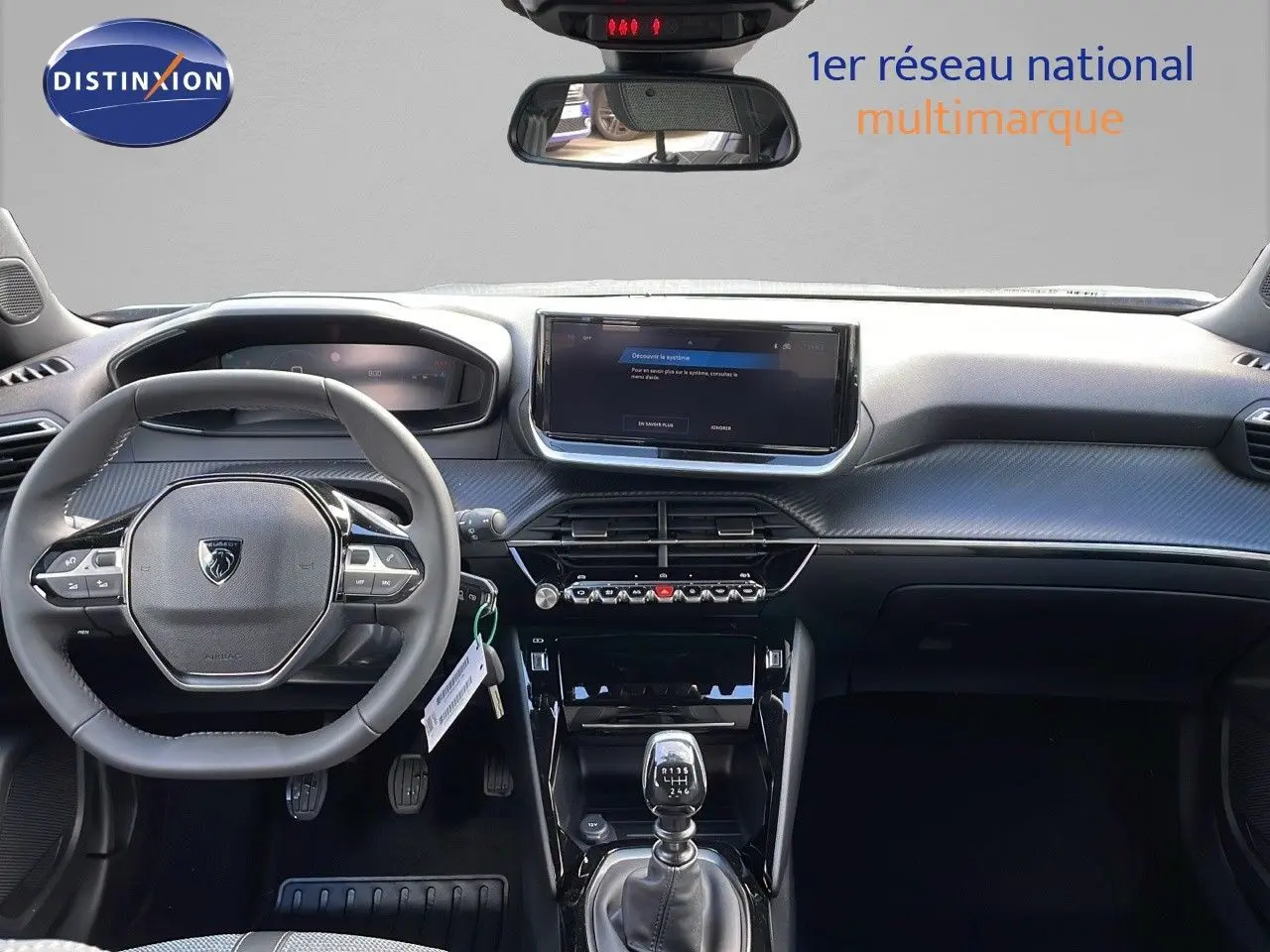 Intérieur Peugeot 2008 2025 vue de face, tableau de bord gris avec volant compact et boîte manuelle visible.