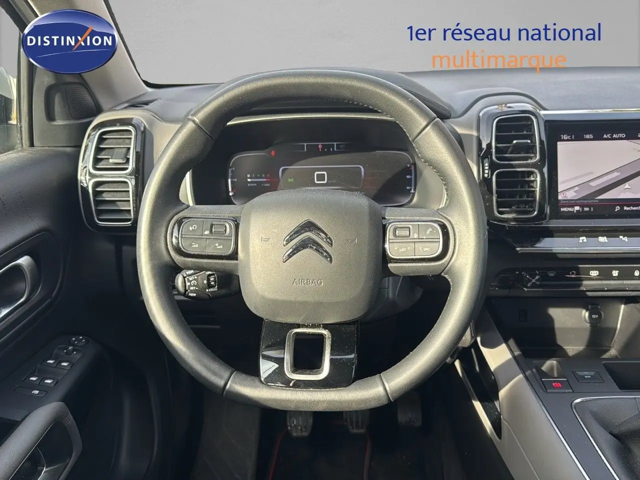 Vue intérieure centrée sur le volant du Citroën C5 Aircross blanc nacré, avec tableau de bord numérique et écran tactile visible.