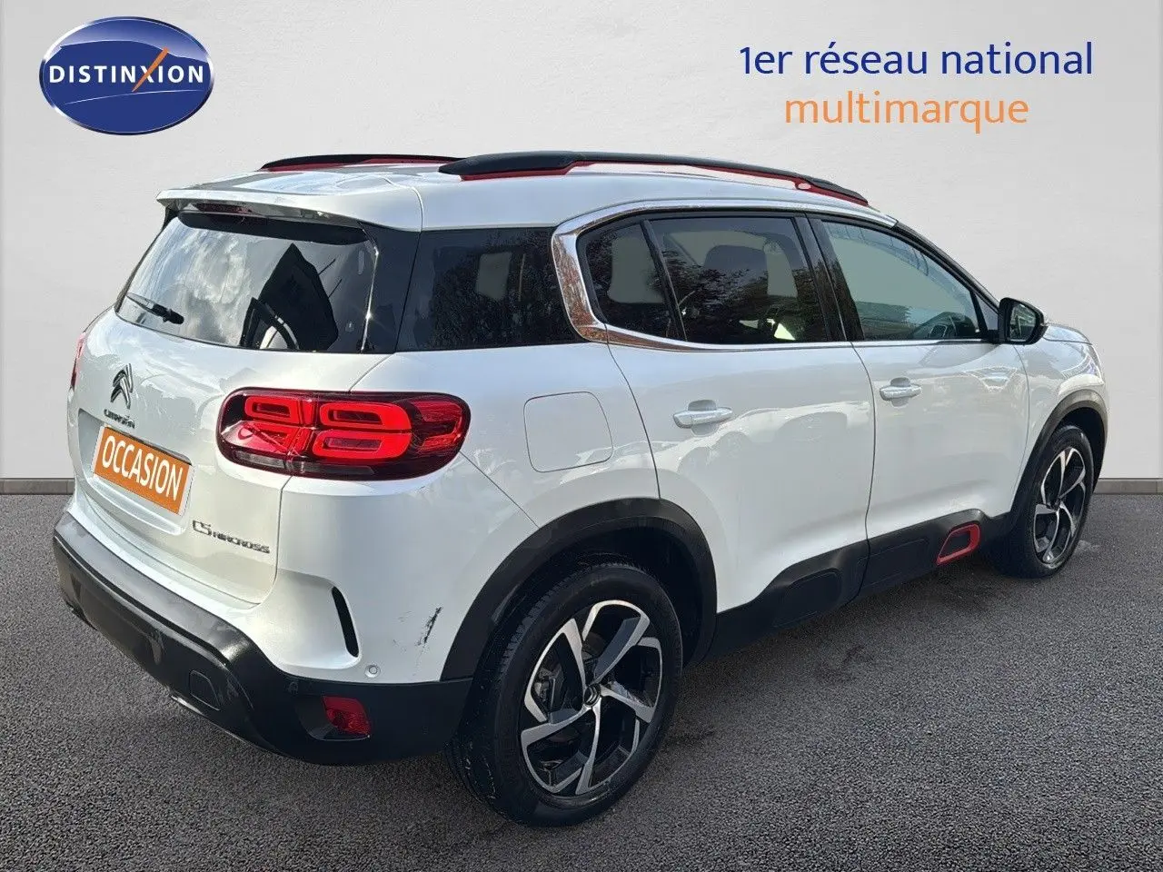 Citroën C5 Aircross blanc nacré vue 3/4 arrière droit, avec jantes noires et détails rouges sur les bas de caisse.