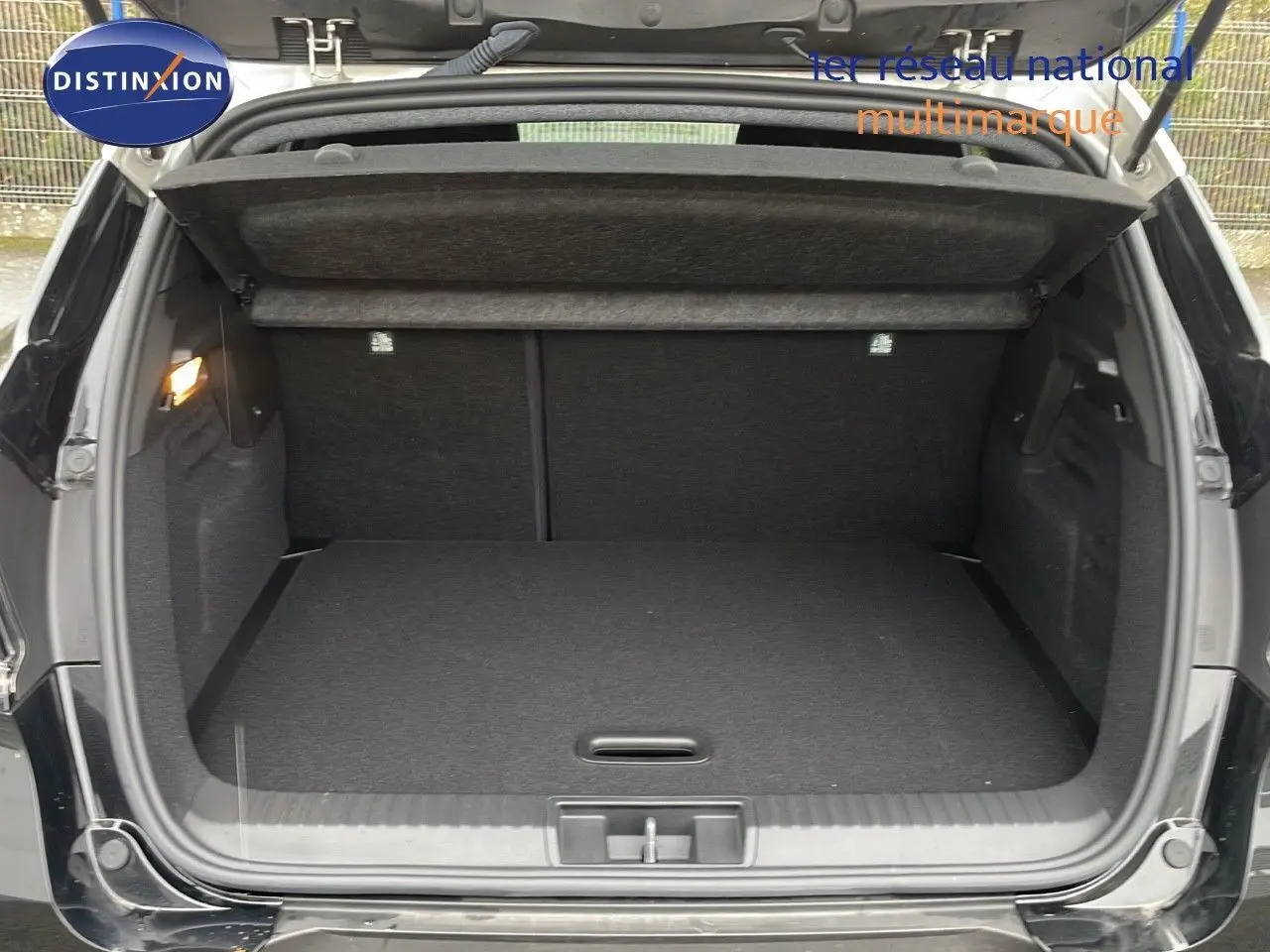 Coffre ouvert d'un Renault Captur E-Tech hybride noir étoile métal avec toit beige, vue arrière montrant l'espace de chargement.