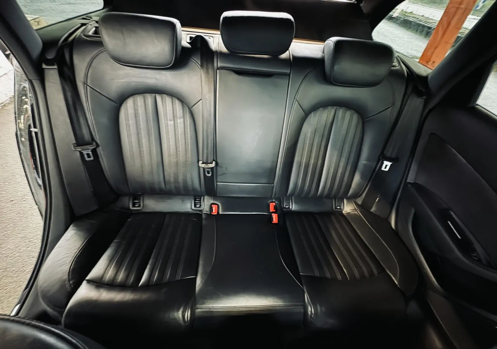 Vue intérieure arrière montrant les sièges en cuir noir de l'Audi A6 Avant Allroad 2016, avec appuie-têtes et ceintures visibles.