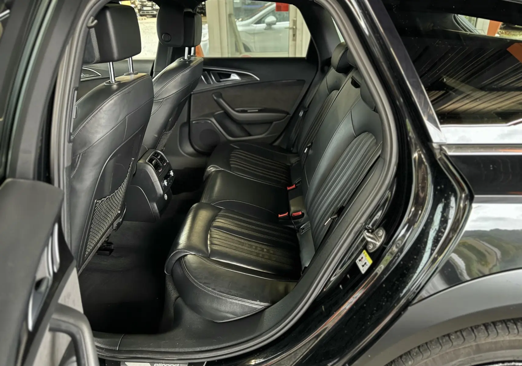 Vue côté droit de l'habitacle arrière noir en cuir de l'Audi A6 Avant Allroad 2016 avec porte ouverte.