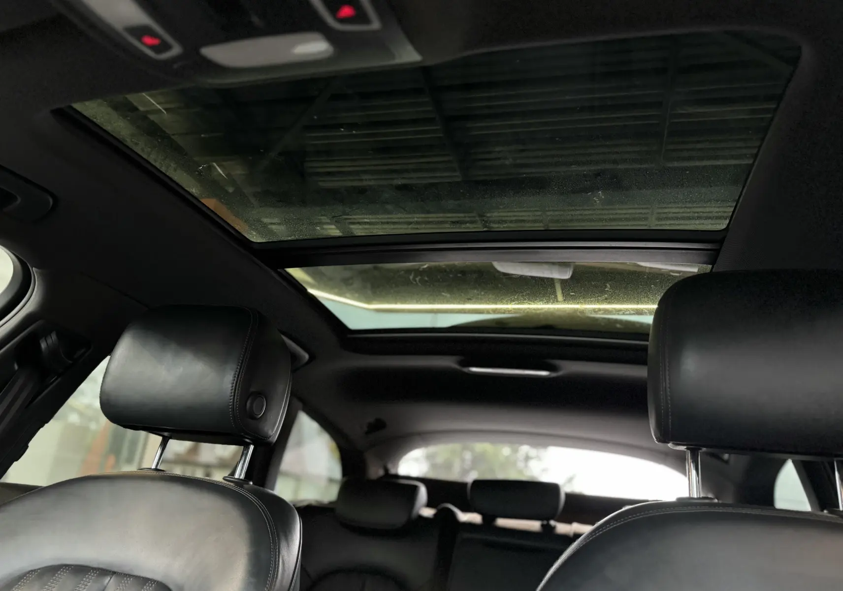 Vue intérieure arrière montrant les appuie-têtes en cuir noir et le toit ouvrant panoramique de l'Audi A6 Avant Allroad 2016.