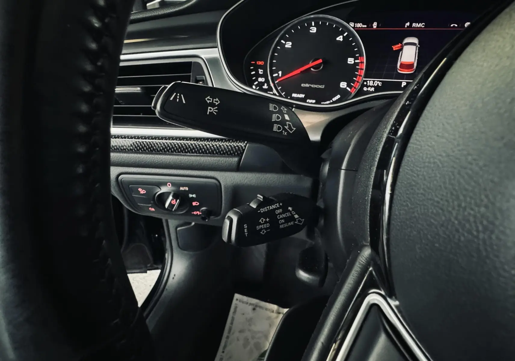 Gros plan sur le tableau de bord noir de l'Audi A6 Allroad, avec commandes au volant et affichage digital du compteur.