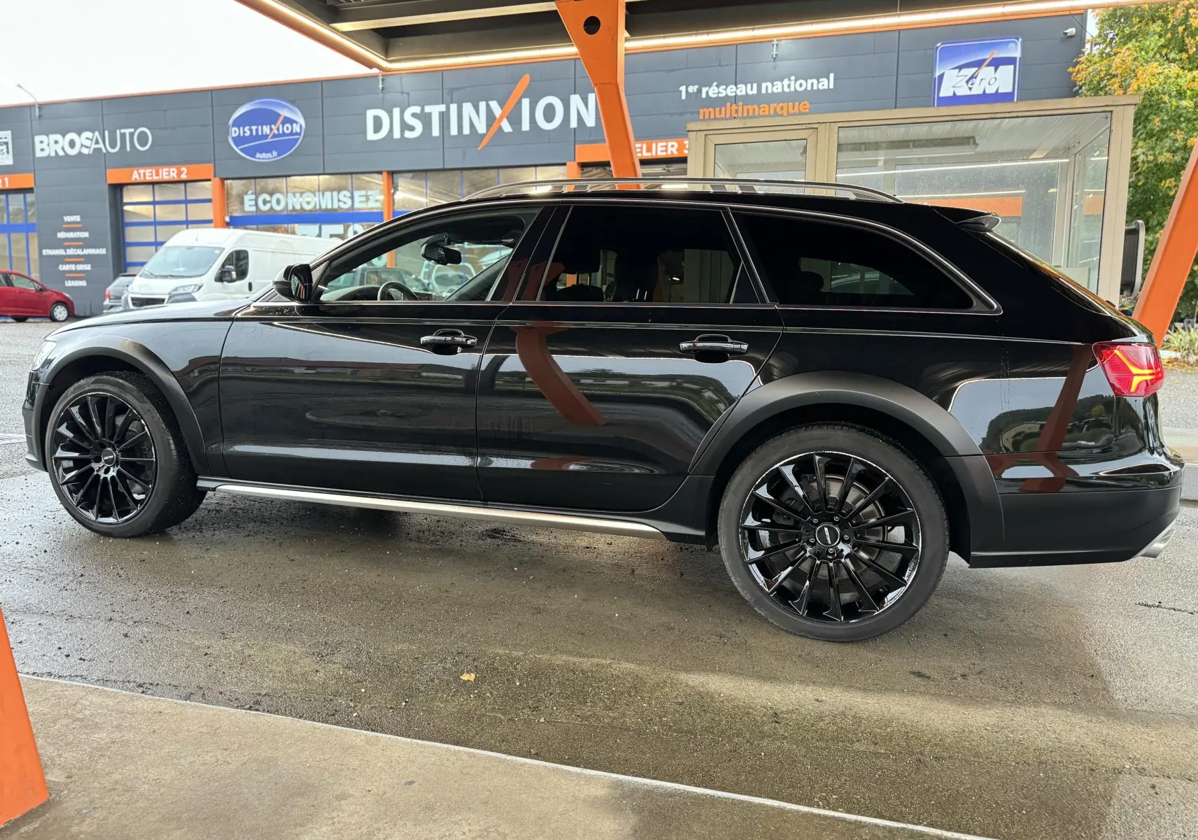 Audi A6 Avant Allroad noire vue de profil côté gauche, avec jantes noires et détails de carrosserie spécifiques.