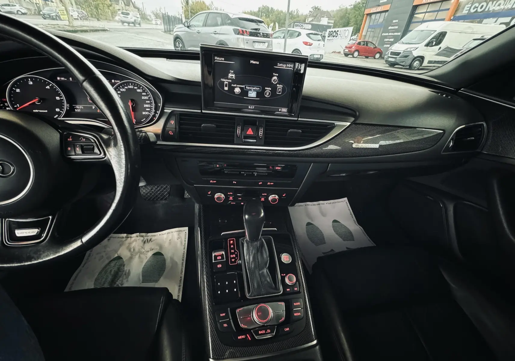 Vue intérieure de l'Audi A6 Avant Allroad 2016 noire, montrant le tableau de bord, la console centrale et l'écran multimédia.