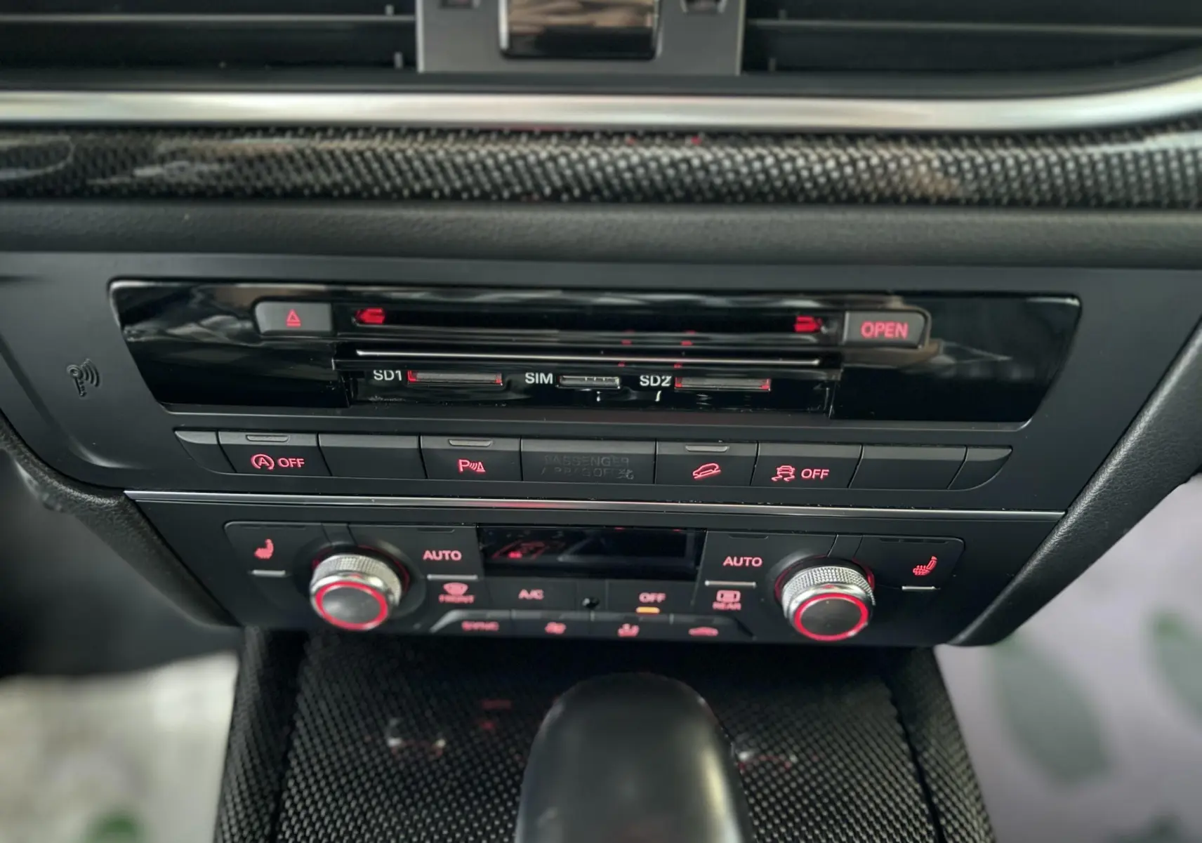 Gros plan sur la console centrale noire de l'Audi A6 Avant Allroad 2016, avec commandes climatisation et bouton de démarrage.