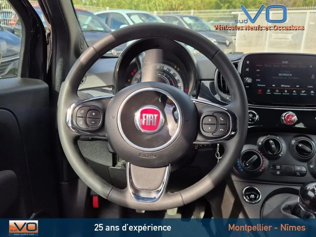 Vue intérieure centrée sur le volant noir de la FIAT 500C 2024 avec tableau de bord et commandes visibles.