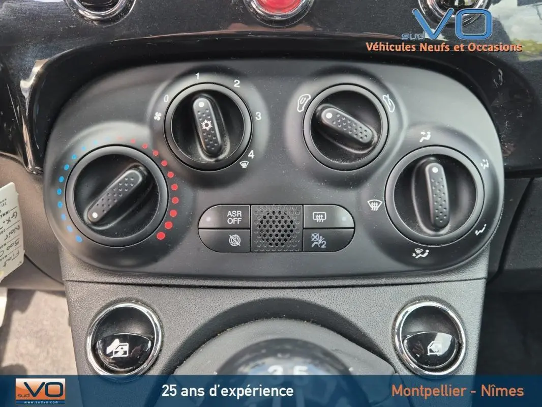Gros plan sur les commandes de climatisation et ventilation du tableau de bord du Fiat 500C noir 2024 hybride.