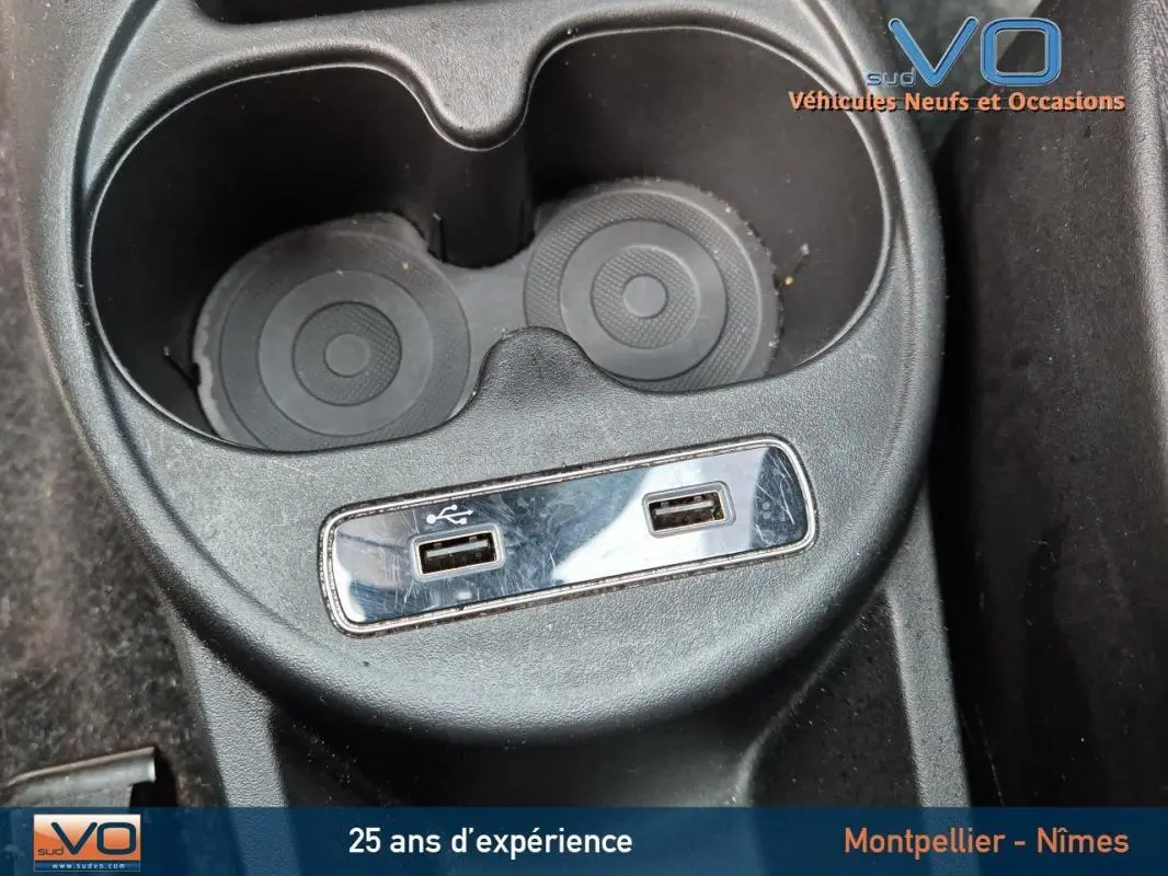 Prise USB double et porte-gobelets noirs dans l'habitacle du Fiat 500C 2024 côté console centrale.