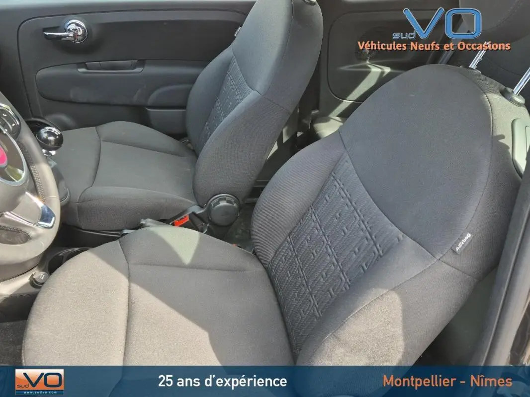 Intérieur de la FIAT 500C 2024 noir, vue côté gauche sur les sièges avant en tissu avec levier de vitesses manuel.