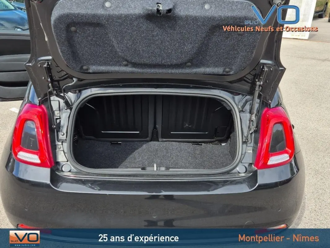 Vue arrière du coffre ouvert d'une FIAT 500C noire 2024, mettant en valeur l'espace de rangement et les feux arrière rouges.