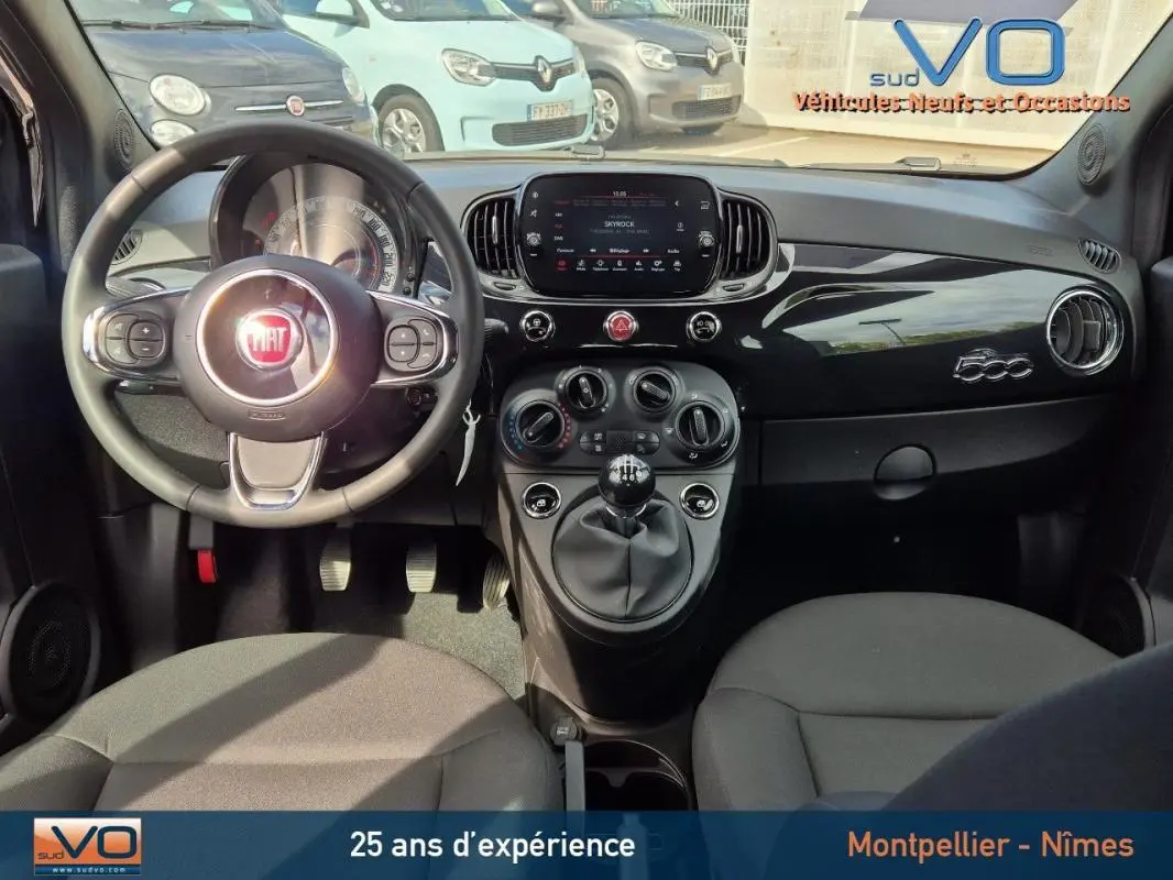 Intérieur avant de la FIAT 500C noire 2024, tableau de bord brillant avec logo 500 et volant multifonction.