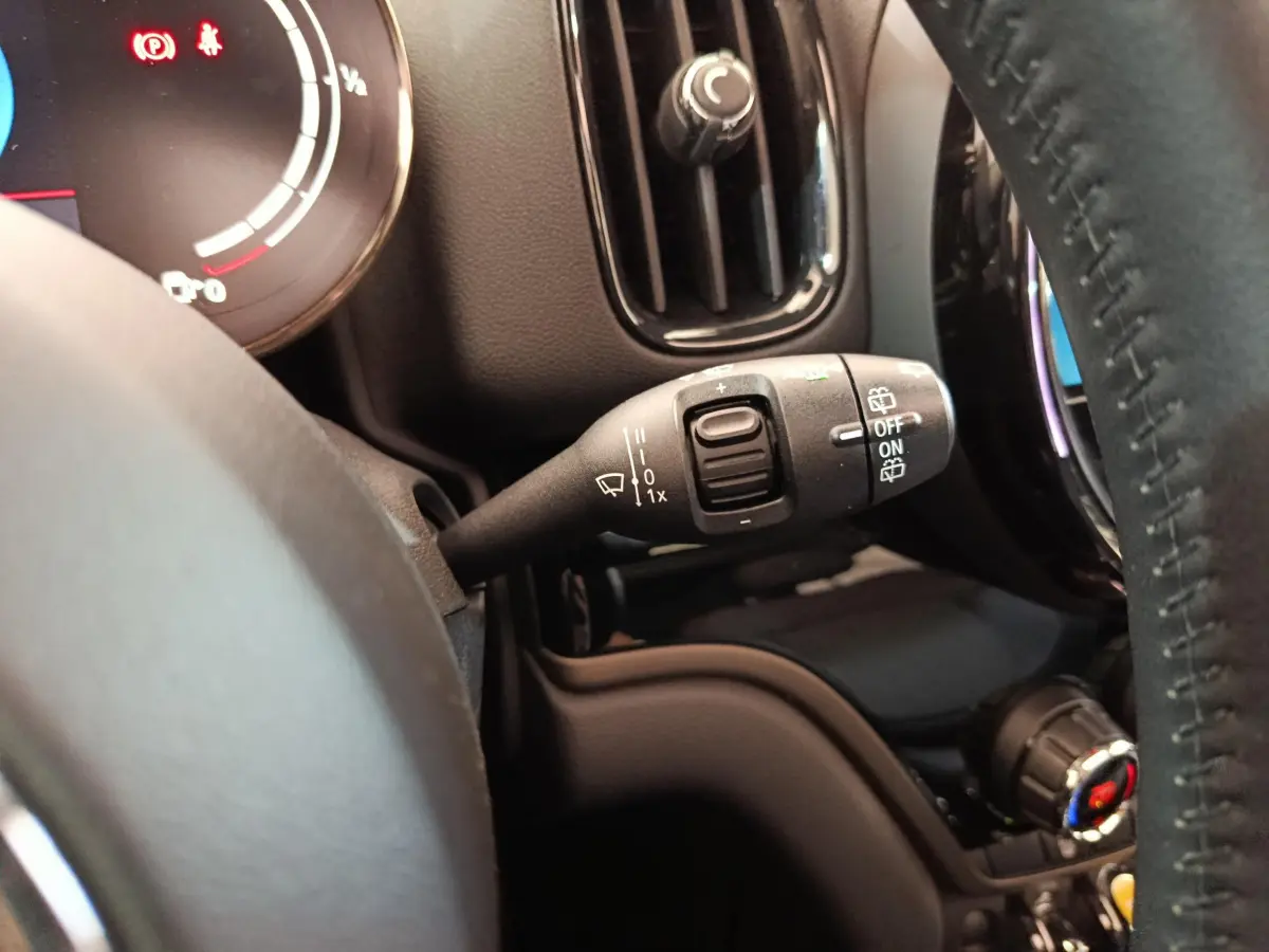 Gros plan sur la commande d’essuie-glace à gauche du volant cuir dans l’habitacle noir du MINI Countryman blanc.