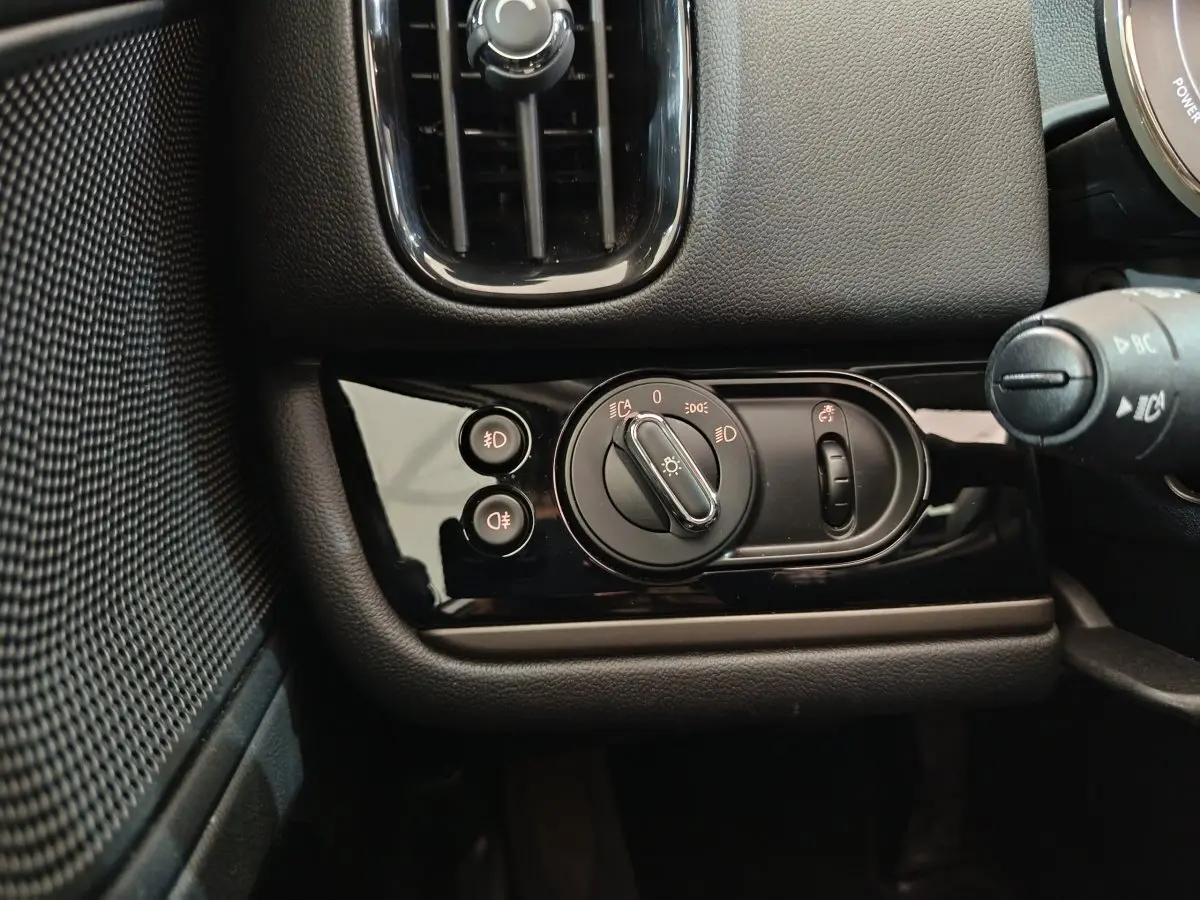 Détail du tableau de bord noir du MINI Countryman 2021 montrant les commandes d'éclairage et la ventilation côté gauche.