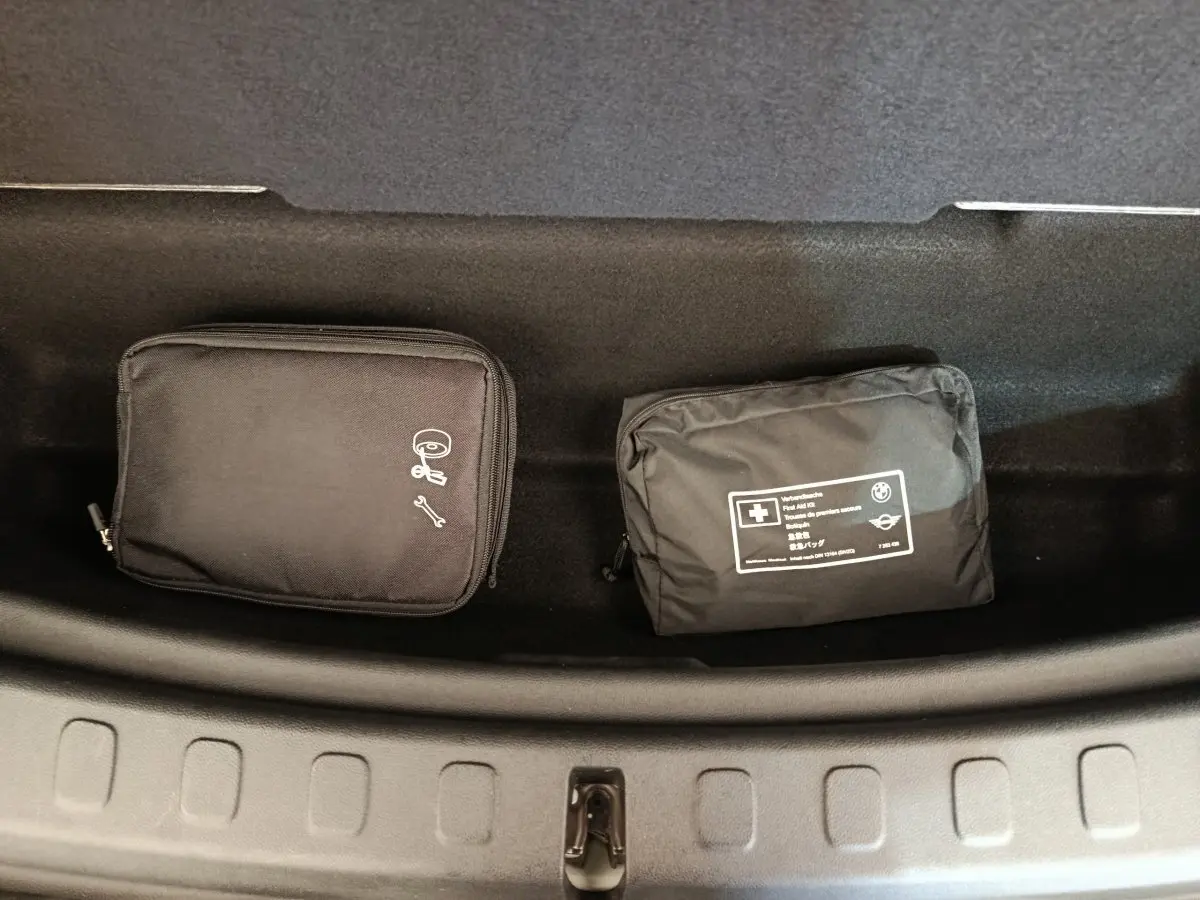 Vue plongeante sur le coffre avant noir d'un MINI Countryman blanc avec trousses de secours et outils rangées.