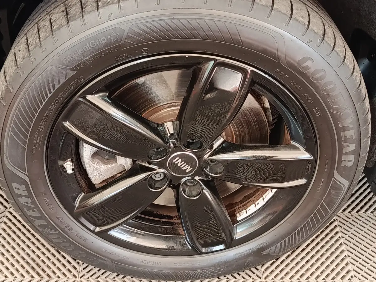 Gros plan sur la jante noire brillante et le pneu Goodyear d'une MINI Countryman blanche hybride rechargeable.