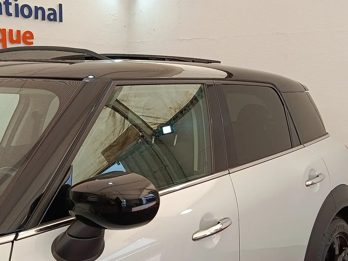 Vue latérale droite du MINI Countryman Cooper SE hybride blanc avec toit noir et rétroviseur noir brillant.