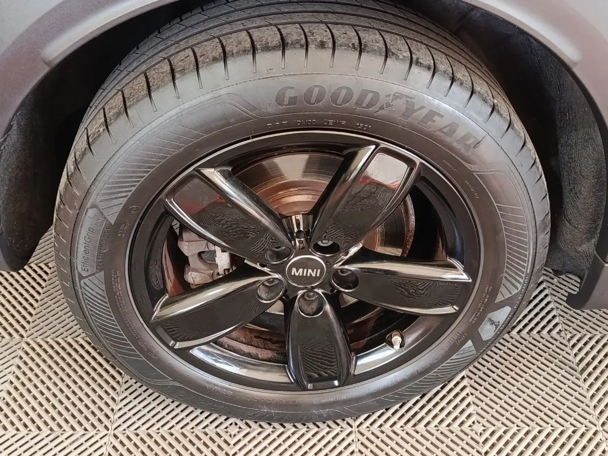 Gros plan sur la roue avant droite noire brillante d'une MINI Countryman blanche, avec pneu Goodyear visible.