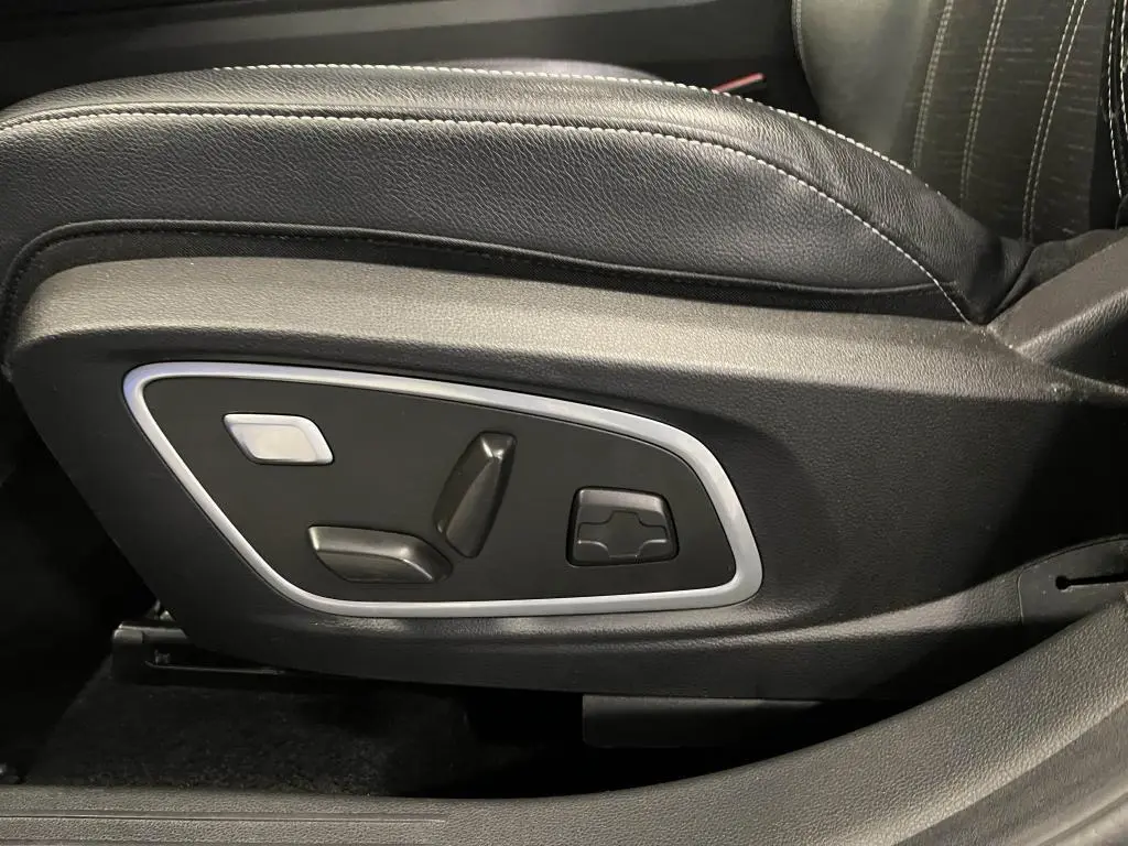 Gros plan sur les commandes électriques du siège conducteur noir avec surpiqûres argent du Renault Austral bleu 2023.