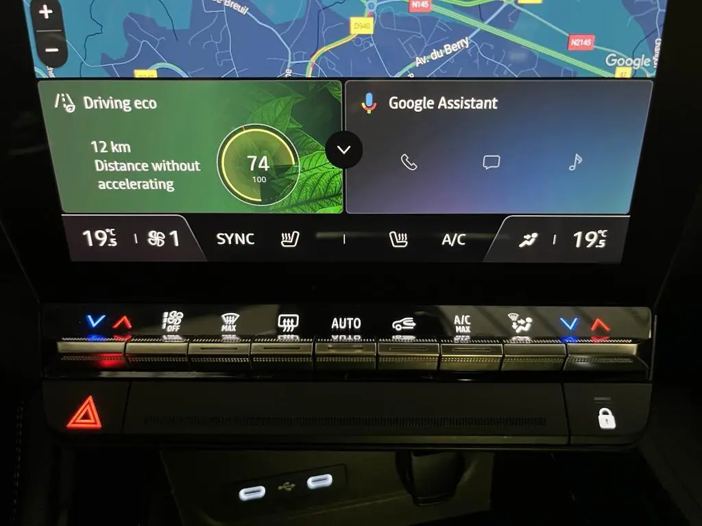 Gros plan sur la console centrale tactile du Renault Austral bleu, affichant la navigation et commandes climatisation.