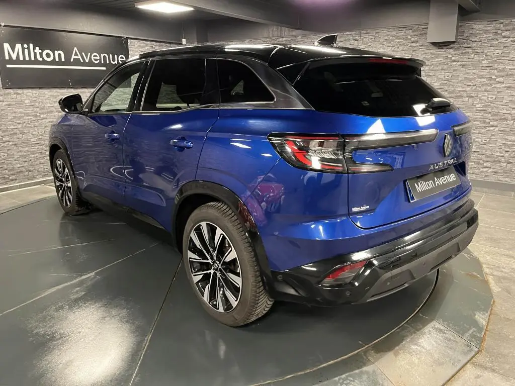 Vue 3/4 arrière droite d'un Renault Austral bleu avec toit noir et jantes alliage noires diamantées.