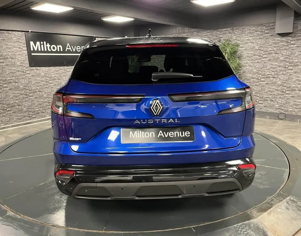 Vue arrière d'un Renault Austral bleu avec hayon motorisé et toit noir étoilé dans un showroom.