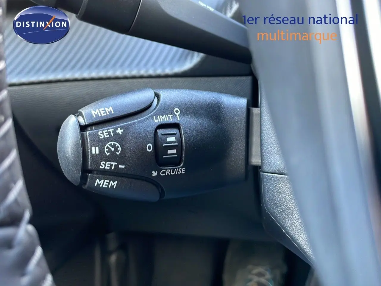 Gros plan sur la commande de régulateur de vitesse à gauche du volant dans un Peugeot 2008 gris Artense Metal.