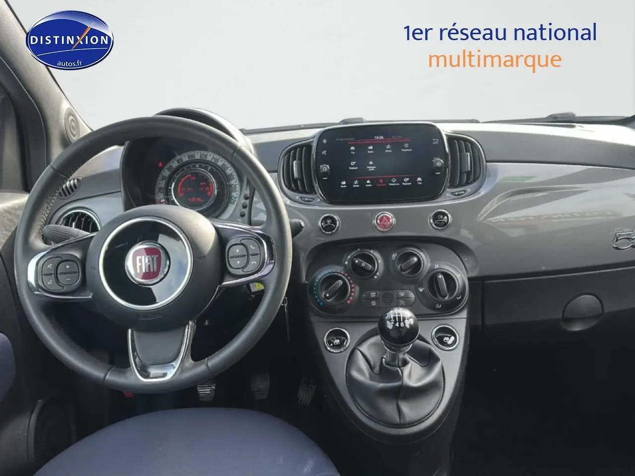 Vue intérieure du tableau de bord gris de la Fiat 500 2022 avec volant cuir multifonction et boîte manuelle.