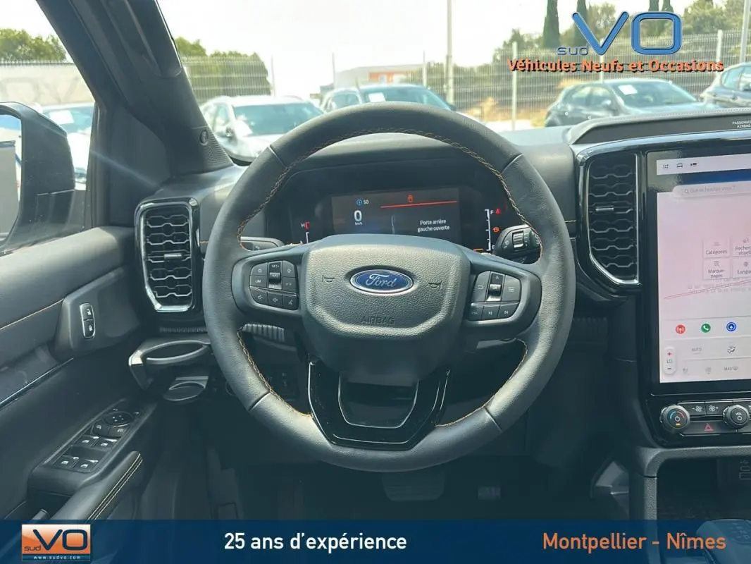 Vue intérieure centrée sur le volant multifonctions du Ford Ranger Wildtrak 2025 avec écran tactile et commandes au volant.